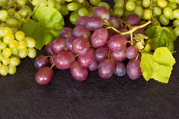green and pink grapes on a wooden background close-up. background with green and red grapes and vine.