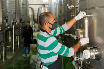 Winemaker in protective masks analyze the white wine in a beaker