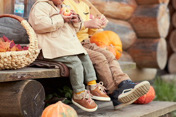 two sitting in autumn clothes on the steps next to a pumpkin