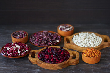 mix of colored beans in wooden bowls on the table close-up. background with a variety of beans.