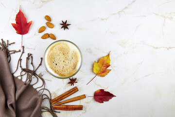 Autumn composition. Cup of coffee with milk, autumn leaves and plaid on grey background. Flat lay, top view.