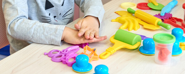 3 years girl creative arts. Child hands playing with colorful clay plasticine. Self-isolation Covid-19, online education, homeschooling. Toddler girl studying at home, home learning