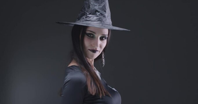 Gothic mystical girl in black hat looking at the camera and smiles, the celebration of Halloween, portrait of a beautiful young woman.