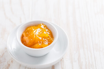 Lemon curd or fruit jelly in small bowl on wooden background