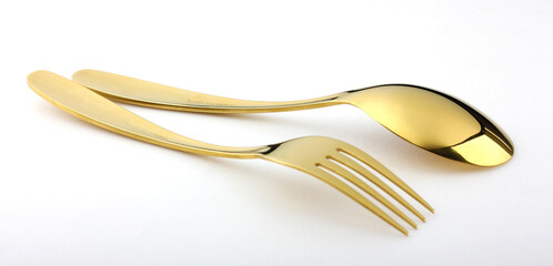 Elegant and expensive golden spoon and fork are placed on a white background.