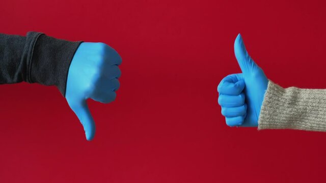 Pandemic conflict. Quarantine pros and cons. COVID-19 outbreak hygiene measures. Hands in blue protective gloves showing opposite approval disagreement gestures isolated on red background loop.