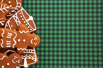 Tasty homemade Christmas gingerbread cookie of various shapes with sugar glaze on a green checkered background with copy space. Merry Christmas card