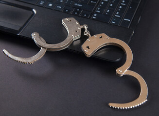 Police metal handcuffs and computer keyboard.