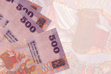 500 Sri Lankan rupees bills lies in stack on background of big semi-transparent banknote. Abstract...