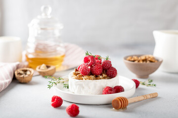 brie cheese with raspberries, honey, walnutsw and thyme . Selective focus, white background