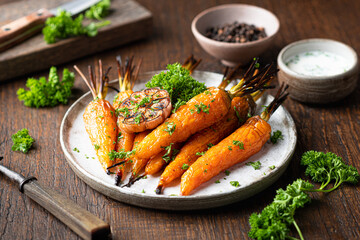baked carrots on a plate on a wooden table, selective focus