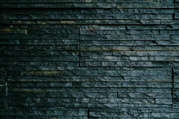 Close-up of a black wall with long thin slabs.