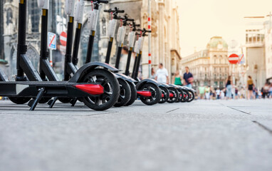 Electric scooters for rent, parked on the sidewalk.