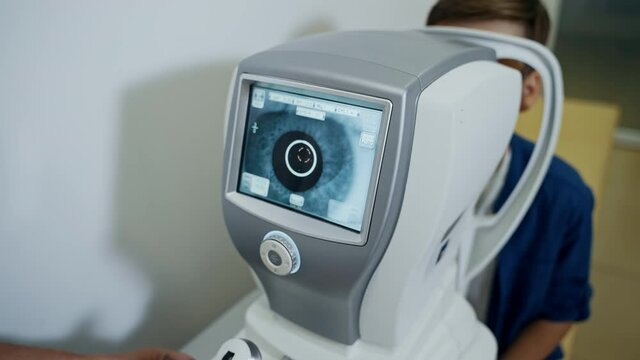 Boy is checking eye sight in clinic. Apparatus in modern clinic. Special technic in ophthalmology cabinet. Pediatric concept.