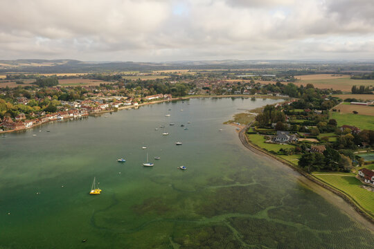 Bosham Harbour at high tide with boats at anchor and the beautiful countryside of West Sussex.