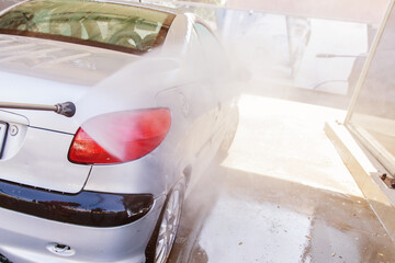Washing car with high pressure washer at self-service car wash station