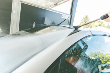 Washing car with high pressure washer at self-service car wash station