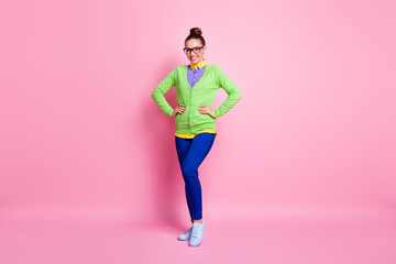 Full length photo of attractive cute young girl hands hips smiling entertain children prepare dancing holiday party wear spectacles colored clothes bright sneakers pink color background
