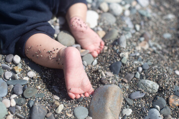 Cute baby feet with sweet fingers and heels. Baby is crawling on the shingle beach. Copy space