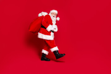You caught me. Photo portrait of scared impressed santa claus with open mouth carrying big bag of presents isolated on vivid red colored background