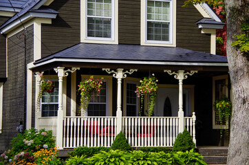 Picturesque street view with historic New England style houses or cottages, flowers and parks in...