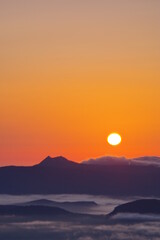 Obraz premium 夜明けの太陽と朝靄の漂う大地、山々のシルエット。北海道、津別峠からの風景。