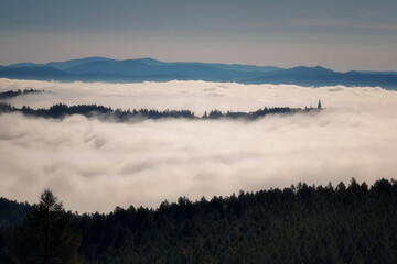 church tower sticking out of the morning mist