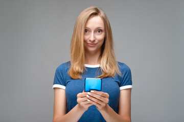 Young woman uses mobile phone. Studio shot, gray background, isolated