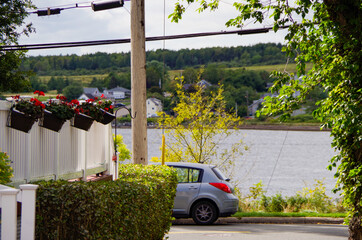 Picturesque street view with historic New England style houses or cottages, flowers and parks in...