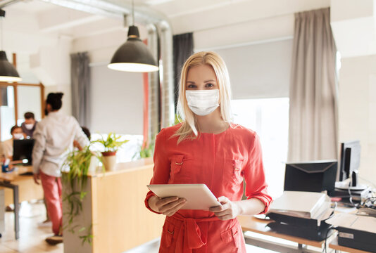 business, pandemic and health concept - businesswoman or creative female office worker wearing face protective medical mask for protection from virus disease with tablet pc computer - Powered by Adobe