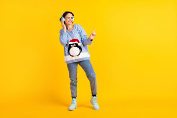 Full length photo of attractive funny lady students party newyear listen cool modern technology earphones disco event wear ugly sweater pullover jeans shoes isolated yellow color background