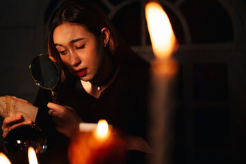 Beautiful young long hair woman fortune teller reading future with manifying glass.