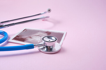 a medical stethoscope and embryo picture on pink background