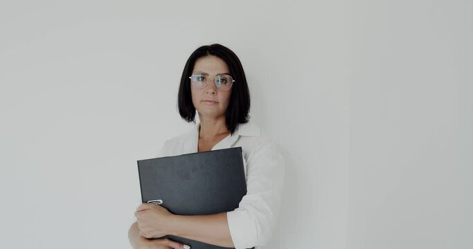 Portrait of teacher with glasses and big black folder in hands looking at camera