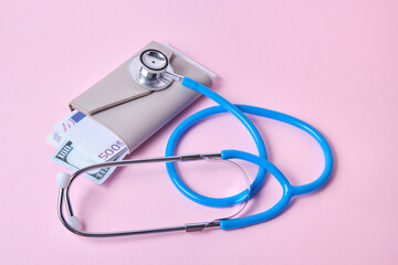 stethoscope and wallet with money, euro and dollar bills, the concept of monitoring income and expenses, savings and financial literacy, pink background