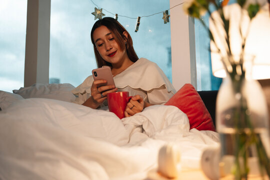 Woman Drinking Hot Milk Before Sleep On A Bed.