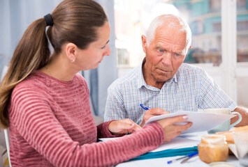 Sad young woman and father with financial documents at home interior