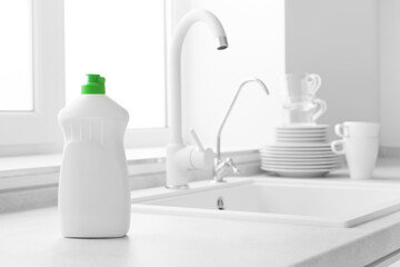 Dishwashing liquid bottle on kitchen sink and clean plates background