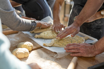 Culinary master class. Closeup of people hands preparing khachapuri. Traditional georgian cheese bread. Georgian food