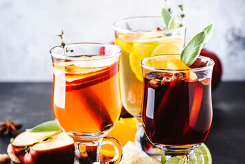 Mulled wine from red and white wine and hot mulled cider. Autumn or winter drinks and cocktails in glass mugs with spices and citrus fruit