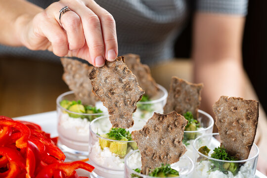 Cups with rye bread, cottage cheese and avocado. Selective Focus och hand and bread.