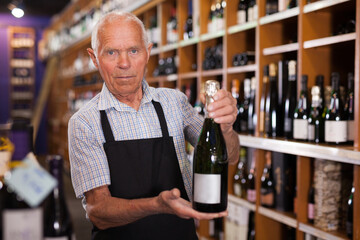 Senior male vintner giving recommendation about purchase wine in his wine house..