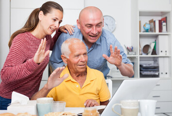 Happy family of three set up a web camera for video calls at home. High quality photo