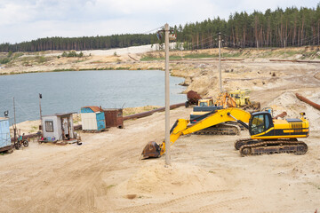 Sand quarry mining industry equipment excavator tractor standing sand land near lake water