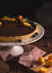 Chocolate tart on a dark background decorated with berries