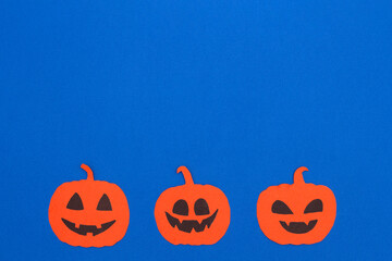 Funny pumpkins faces on blue background. Happy halloween holiday concept, creative greeting card. Top view, flat lay, copy space