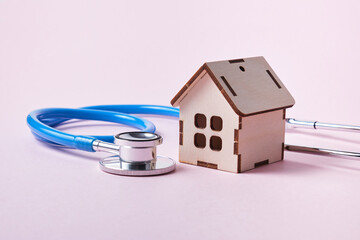 Medical stethoscope and toy house on a pink background with copy space - Powered by Adobe