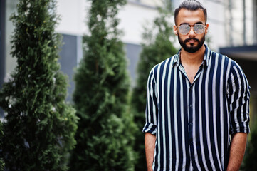 Successful arab man wear in striped shirt and sunglasses pose outdoor.