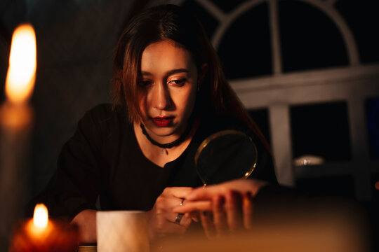 Beautiful young woman fortune teller reading palm hand with manifying glass.