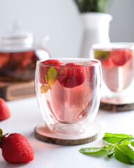 Fruit tea with strawberries and mint in a glass